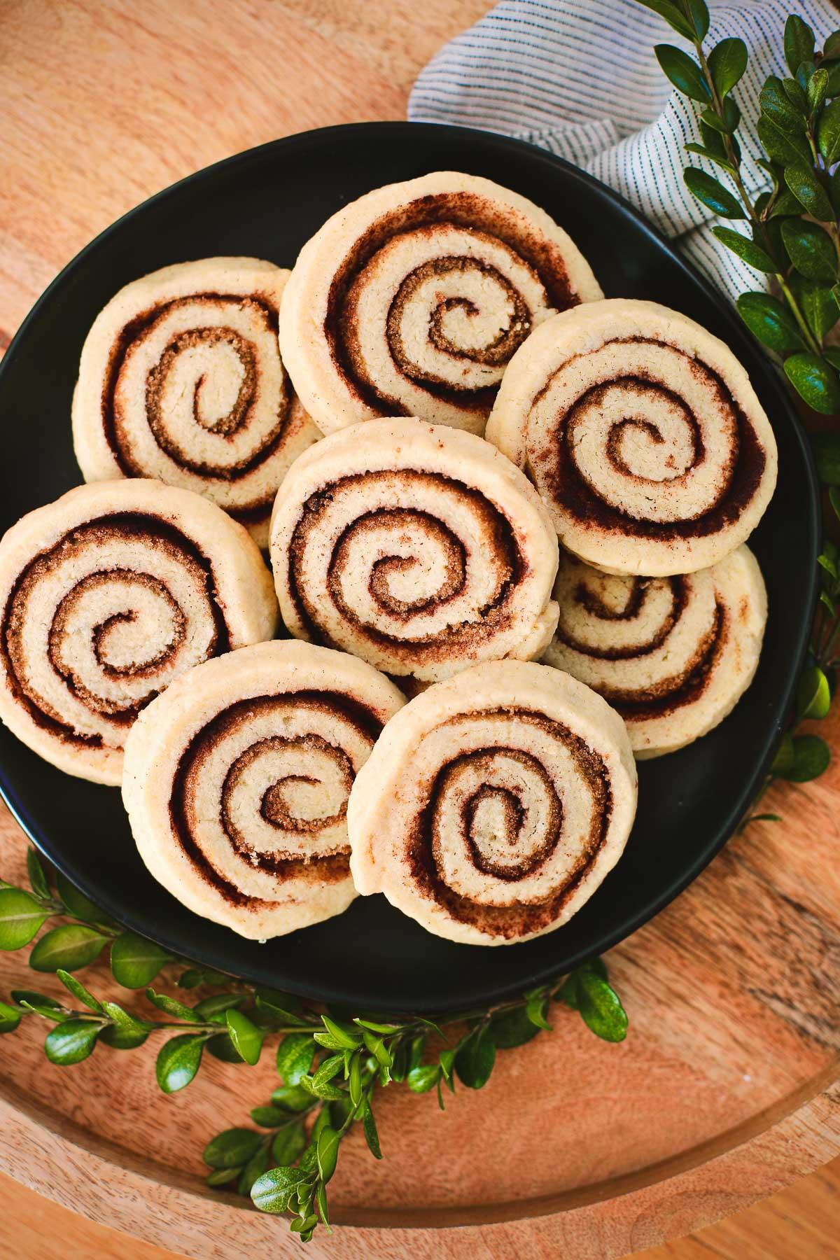 Overhead shot of cinnamon pinwheel cookie dough being rolled and sliced, showing distinct swirl pattern