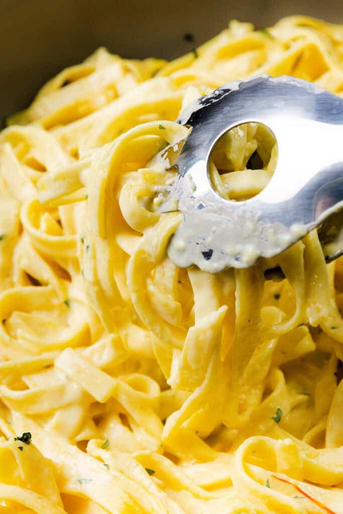 close-up of rich, golden cheese sauce being poured over cooked pasta