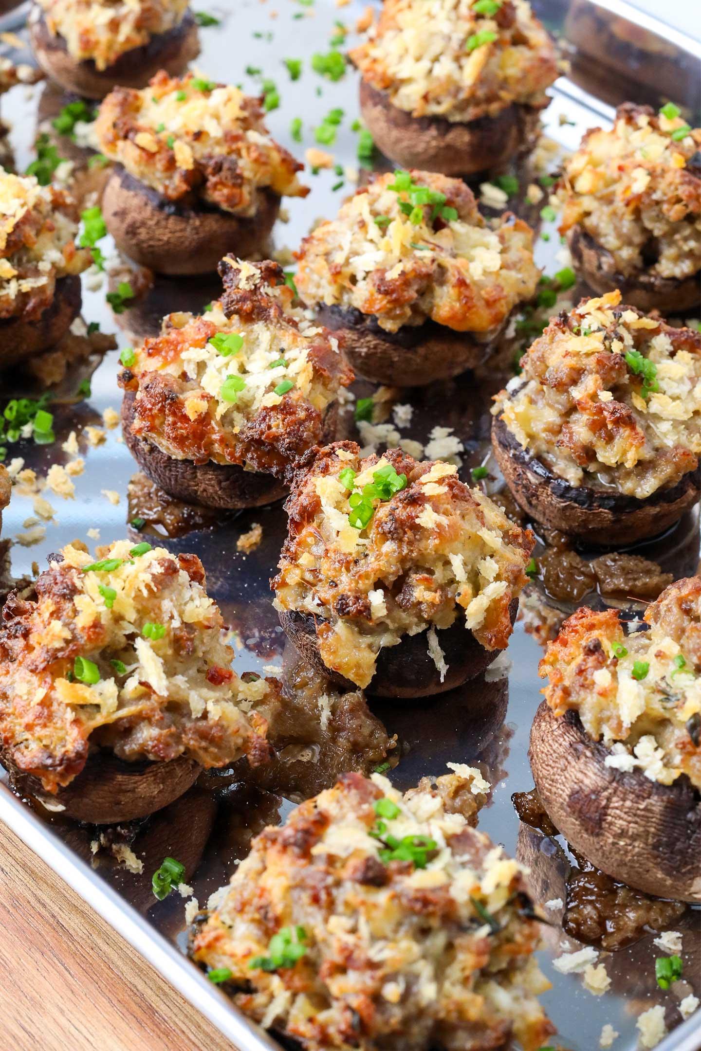 Close-up of golden brown sausage stuffed mushrooms with fresh herbs