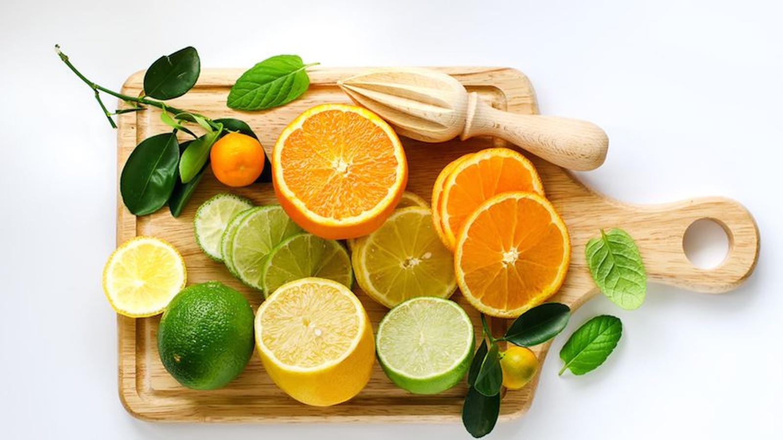 Variety of fresh citrus fruits like oranges, lemons, and limes on a cutting board, ready for juicing