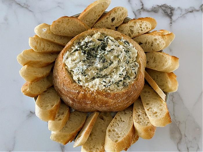 Friends laughing and sharing a bowl of spinach artichoke dip at a casual gathering