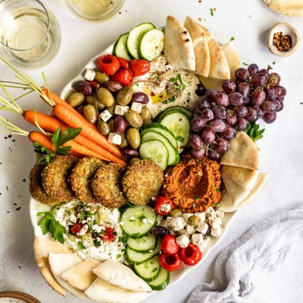 Close-up of a hand reaching for a piece of pita bread from a Mediterranean board