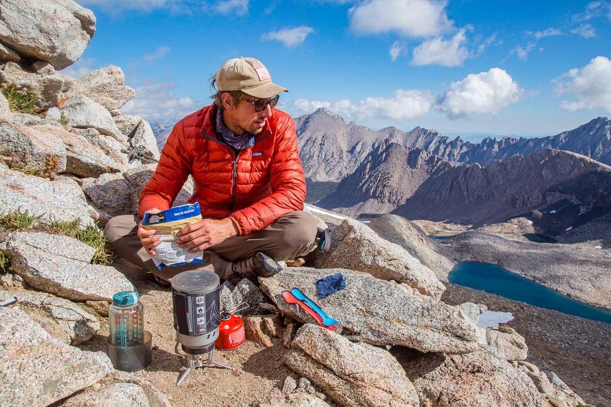 a person hiking in the mountains with a smoothie in hand
