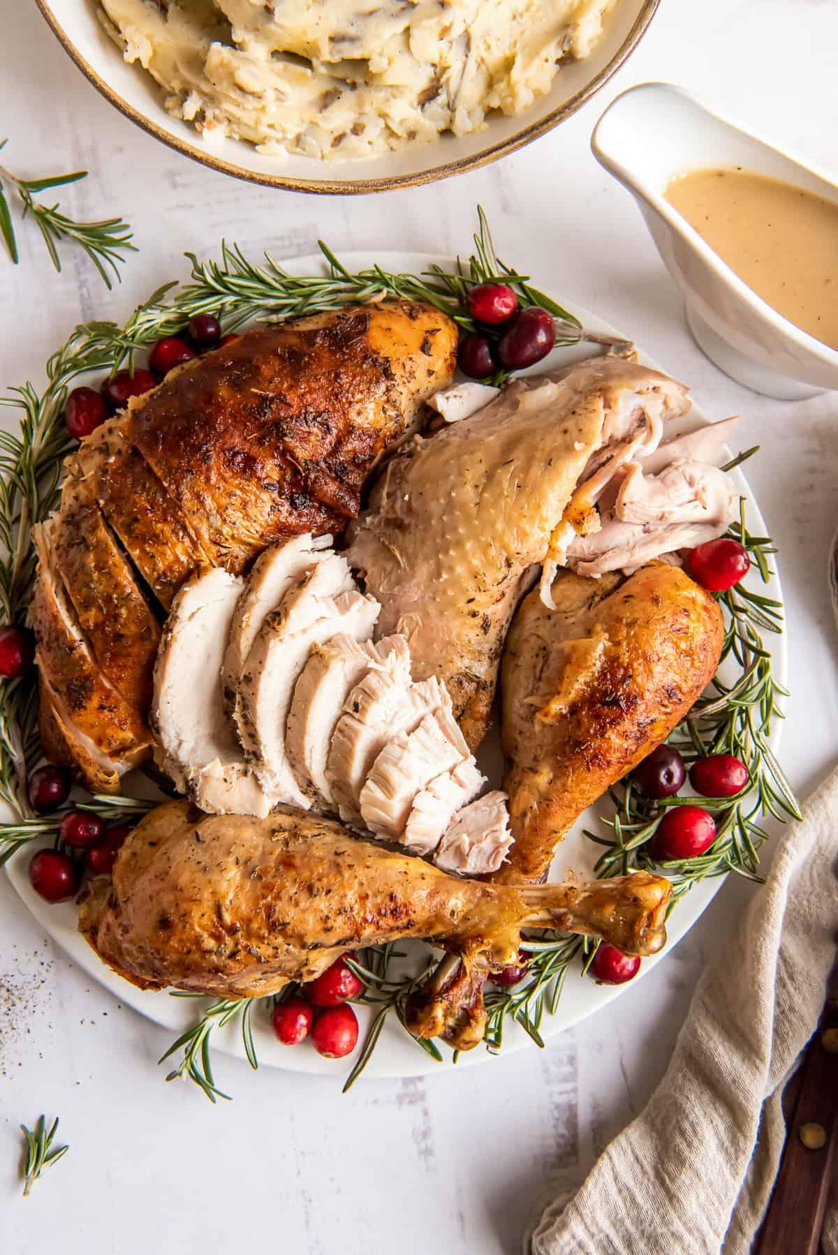 Whole roasted turkey with rosemary and herbs on a platter, golden brown