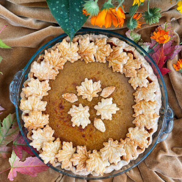 homemade pumpkin pie with golden browned top on a rustic cooling rack, fall decorations