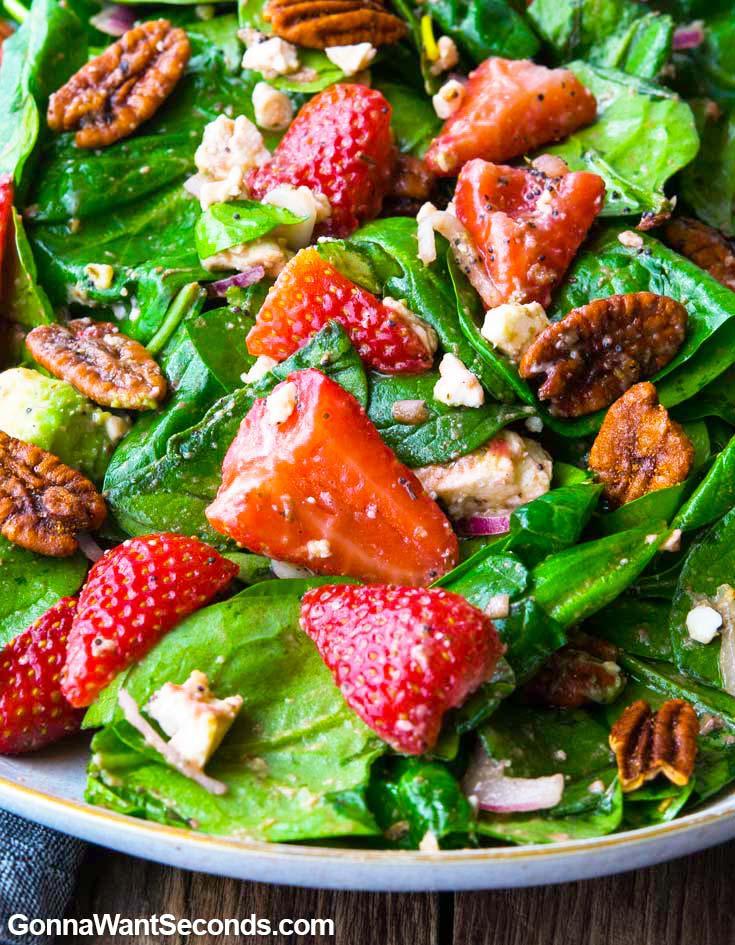 close up of someone enjoying a colorful strawberry spinach salad outdoors