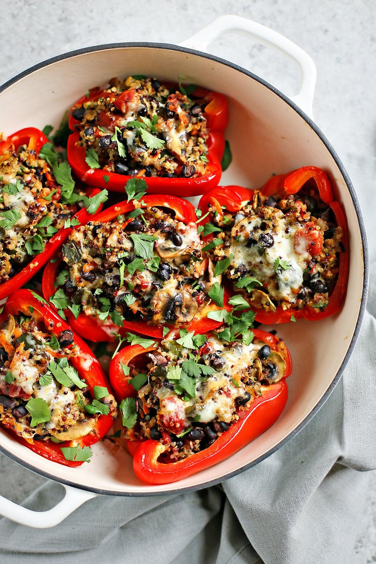 colorful quinoa stuffed bell peppers arranged on a baking sheet, garnished with fresh herbs