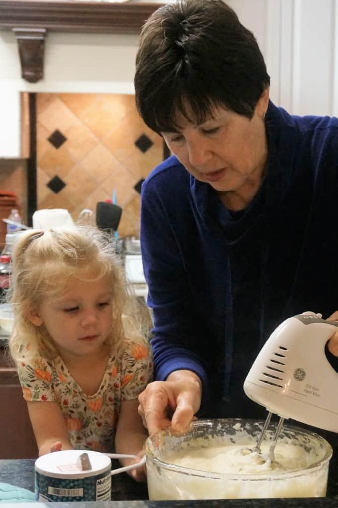 vintage kitchen scene with a grandmother and child mashing potatoes