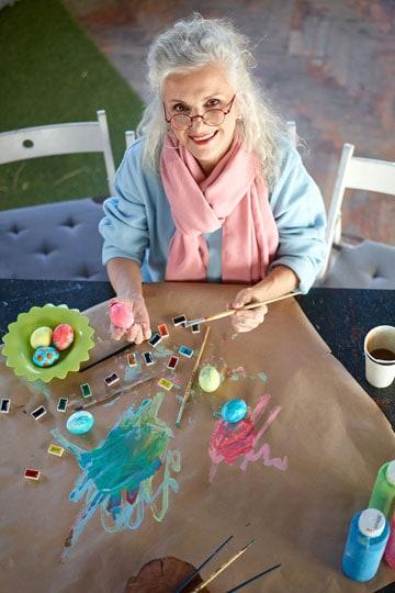 person smiling while holding up a handmade craft project