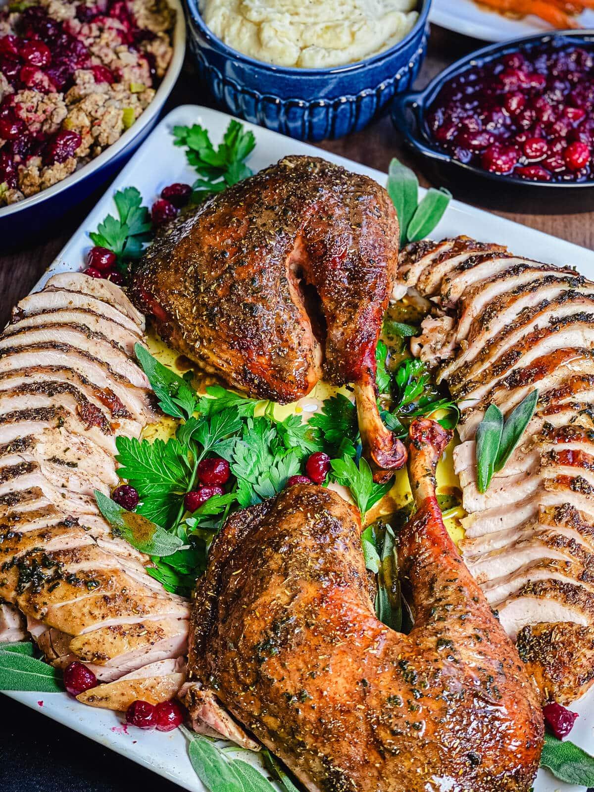 Close-up of a perfectly golden-brown roasted turkey on a carving board with sage garnish