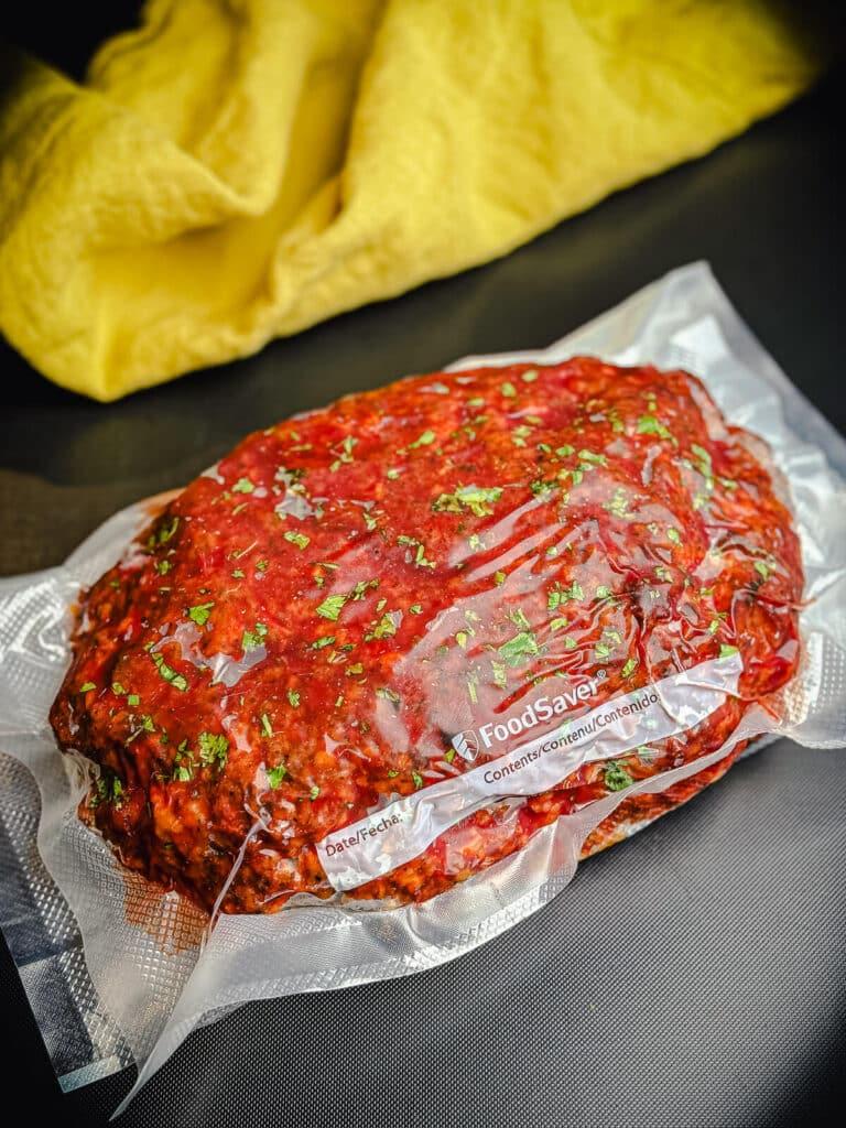 a hand placing a turkey meatloaf into a freezer bag