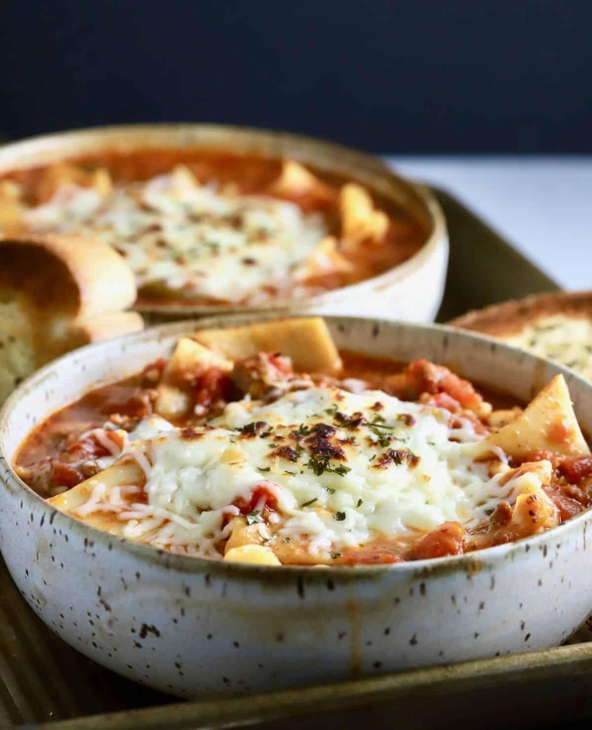 a bowl of steaming lasagna soup topped with cheese