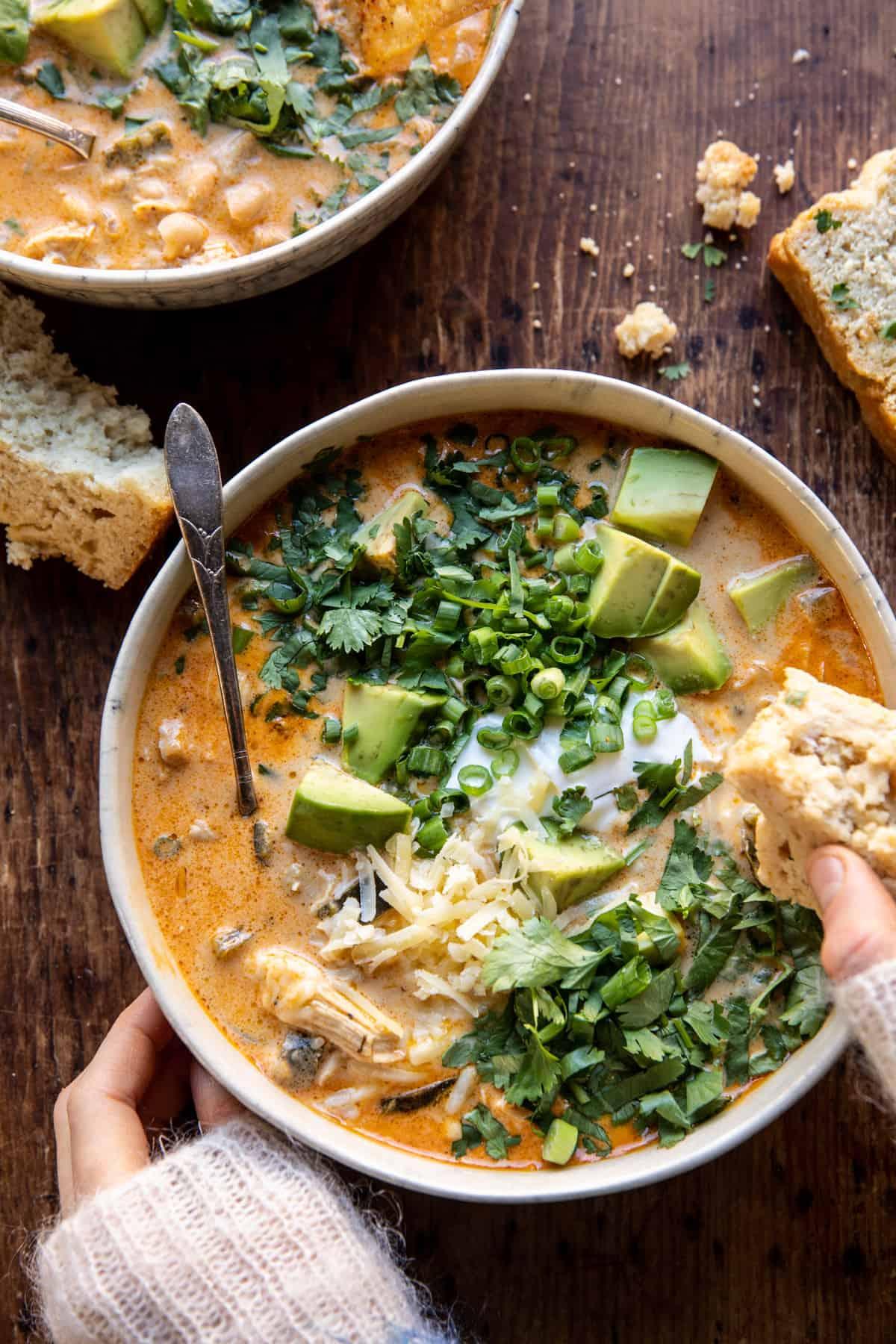 Warm bowl of creamy white chicken chili with garnishes, cozy setting