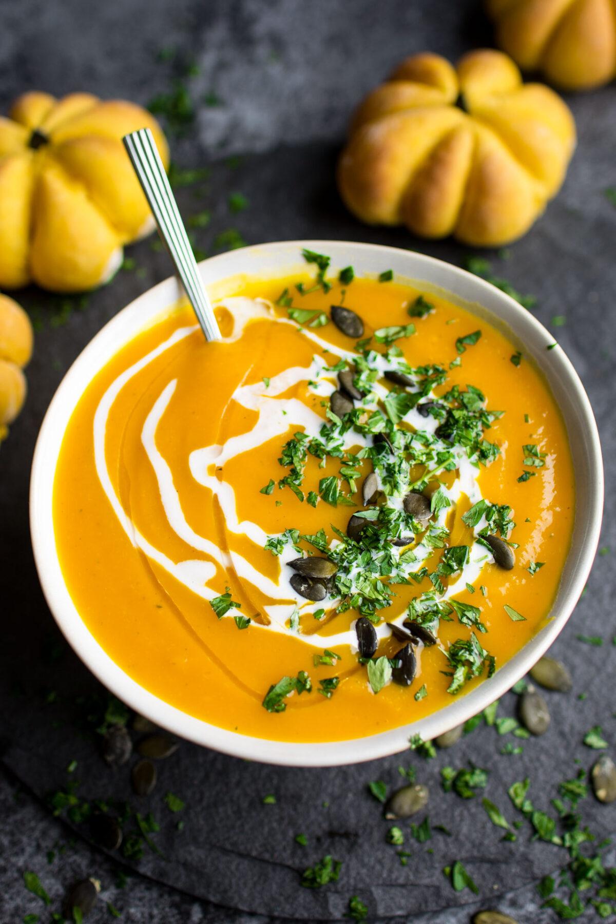 creamy roasted pumpkin sage soup in a rustic bowl with crusty bread and fresh sage
