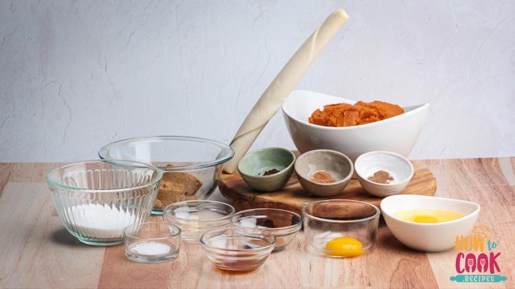 old fashioned mixing bowl with pumpkin pie filling ingredients, spices scattered around