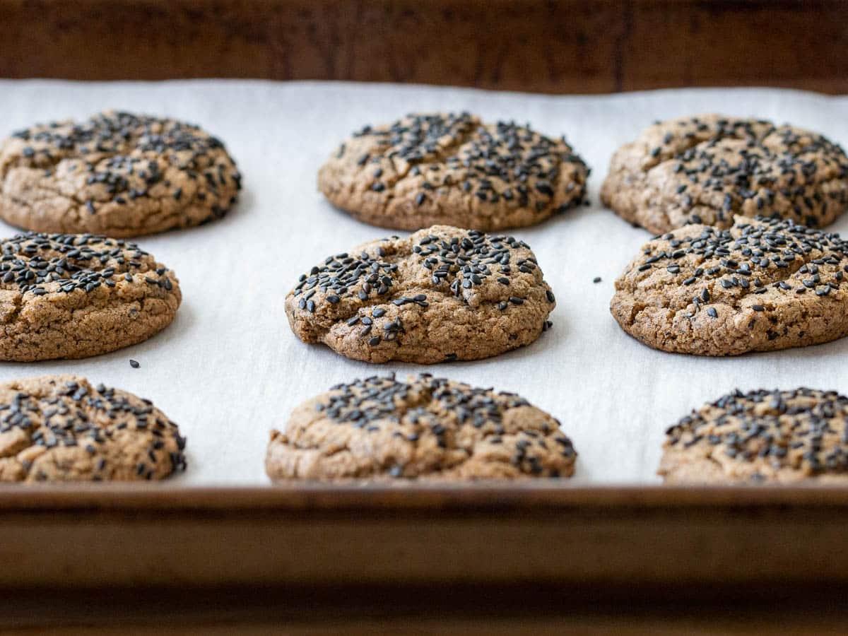 overhead view of a batch of black sesame gluten-free cookies arranged on a wooden board