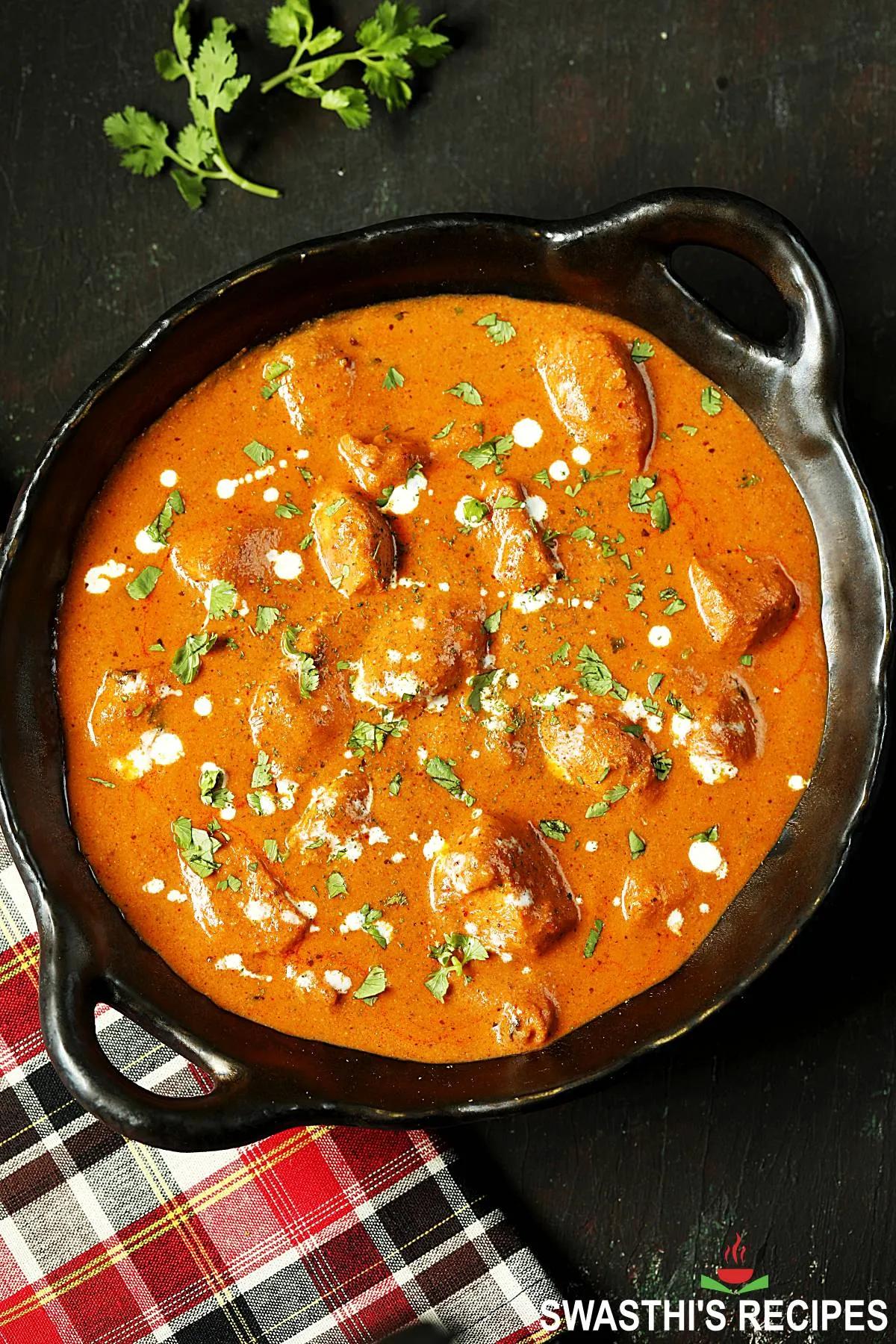a pot of simmering butter chicken on the stove