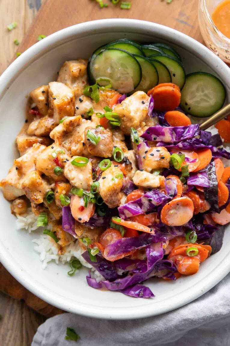 Vibrant Bang Bang Chicken Bowl close up, sweet and spicy sauce, fresh garnishes