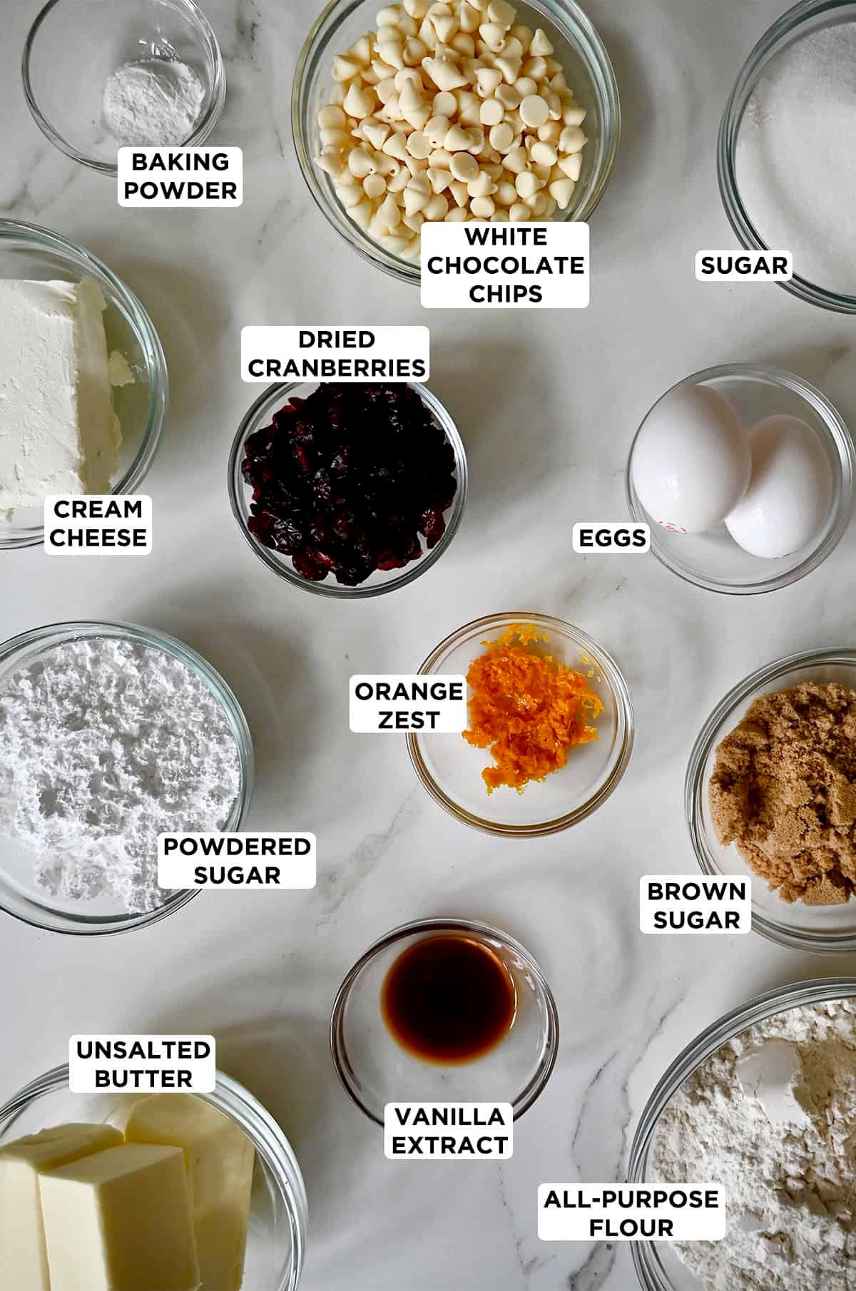 ingredients laid out for cranberry bliss bars: dried cranberries, white chocolate, orange zest, butter, flour