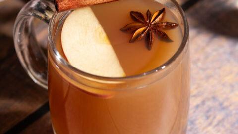 Close-up of sliced apples, cinnamon sticks, and star anise in a pot, ready for spiced drink
