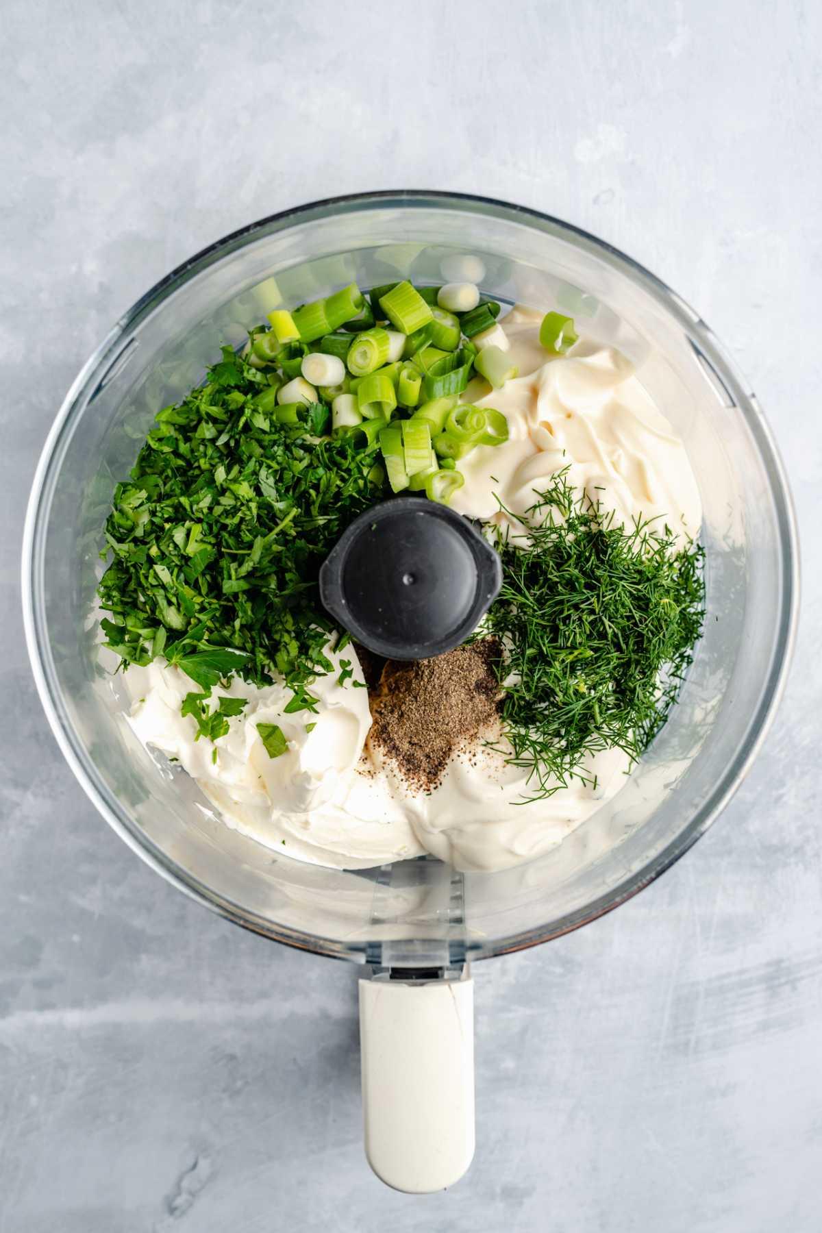 Hands mixing cream cheese and herbs in a bowl
