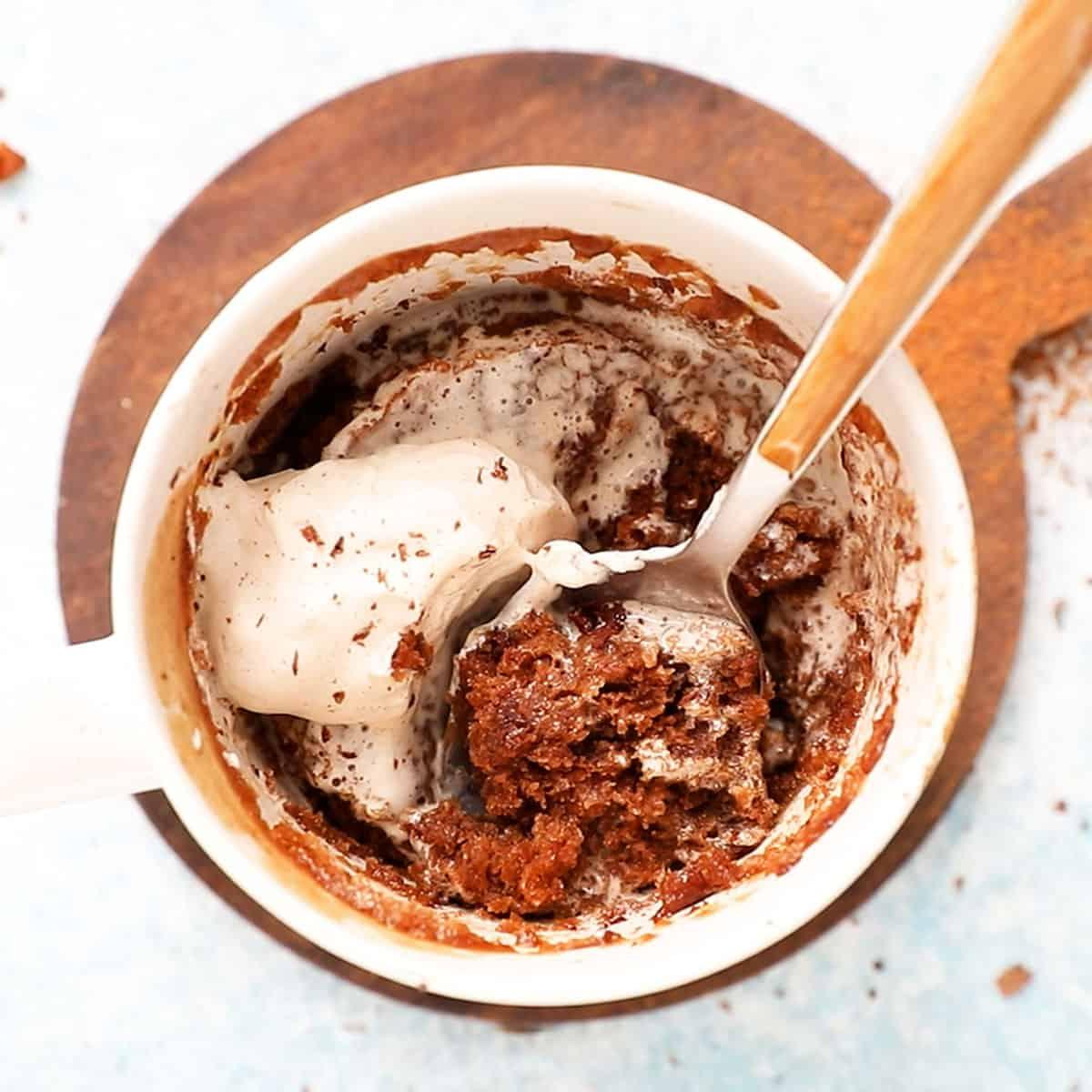 close up shot of a peppermint mocha mug cake in a white mug, with a spoon digging in
