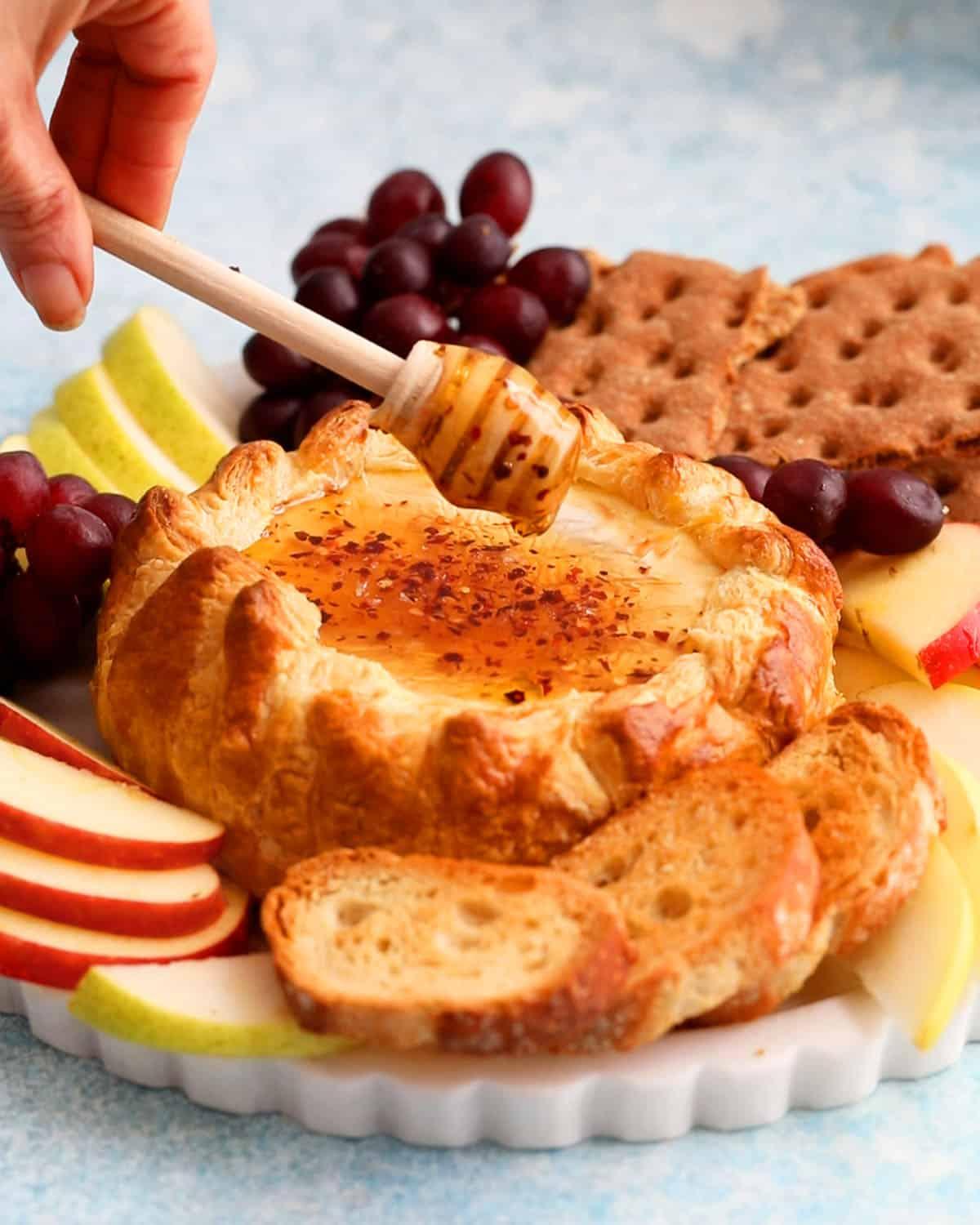 Hand drizzling honey over a warm brie honey tart