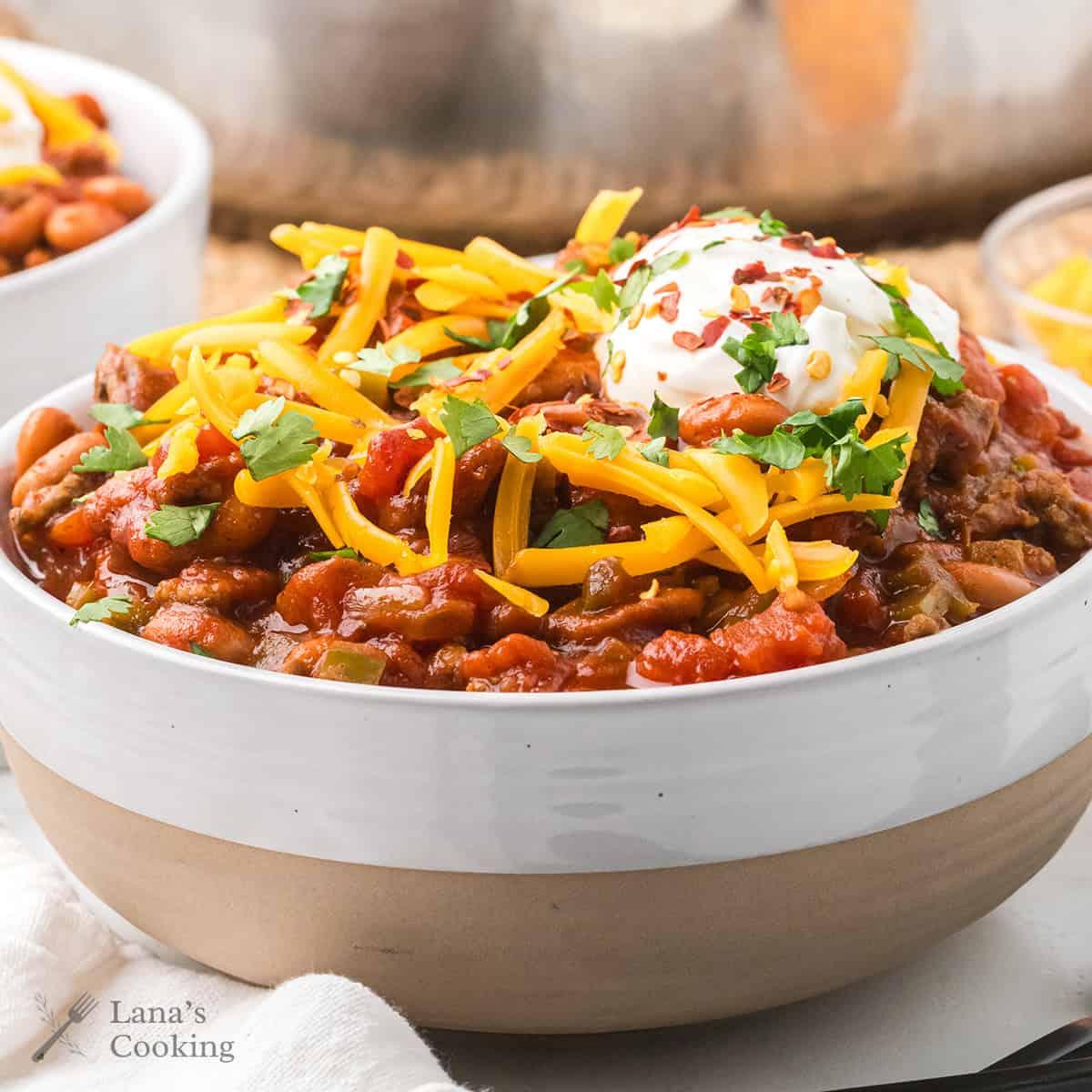 Bowl of chili topped with sour cream, cheese, and cilantro