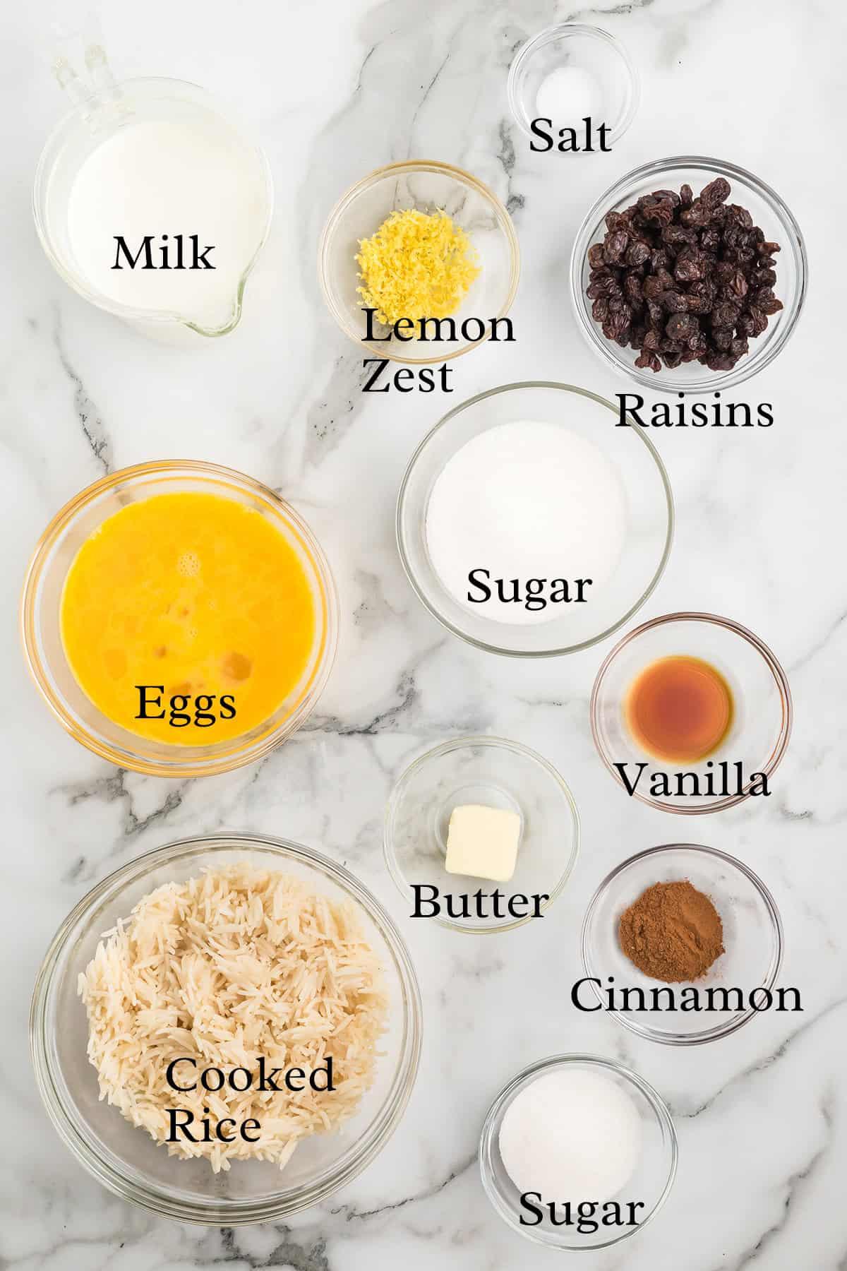 Overhead shot of all ingredients for baked rice pudding laid out on a wooden counter, ready for preparation