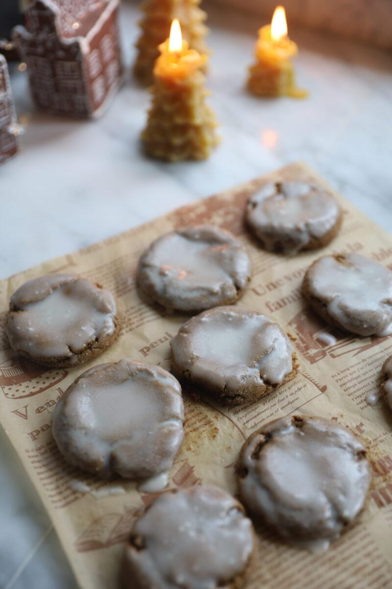 Pile of iced ginger cookies on a plate, some with bites taken out, showing the soft interior