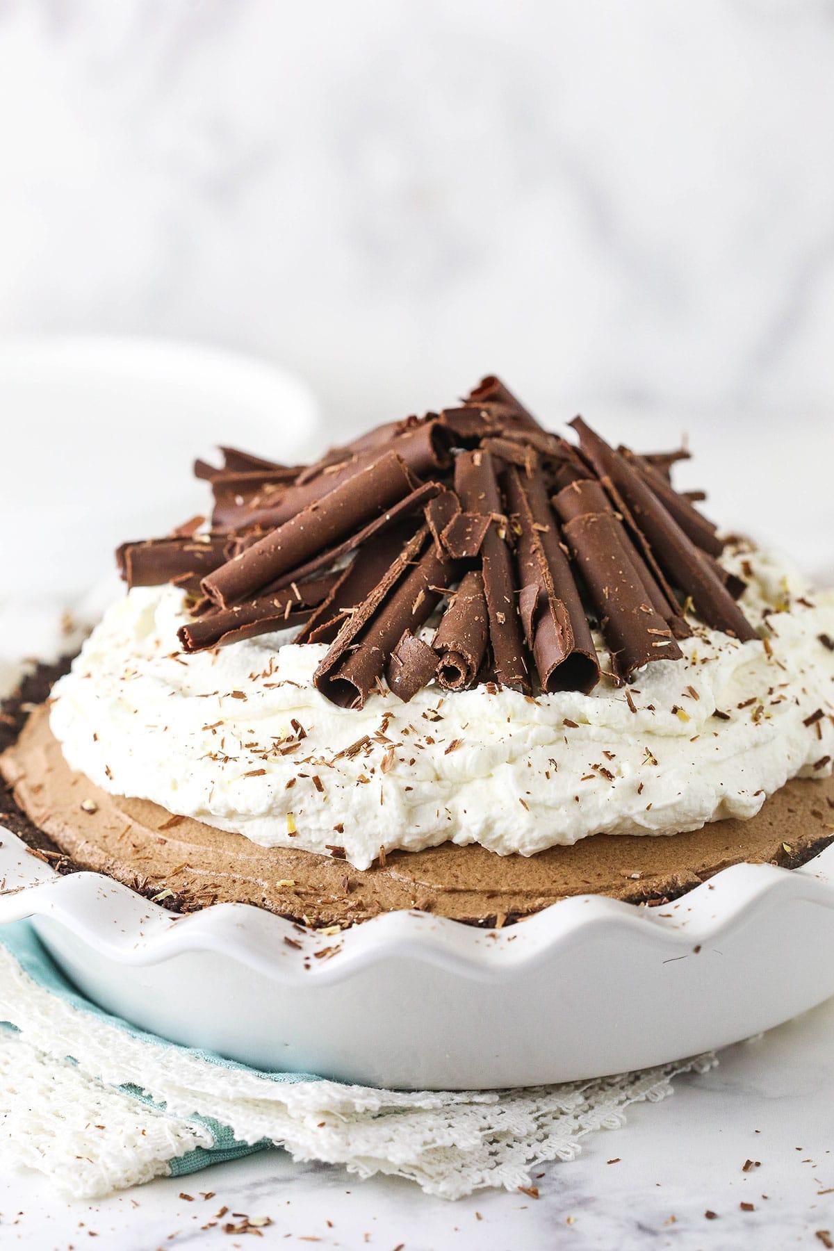 A beautifully set chocolate silk pie on a serving platter, garnished with chocolate shavings and whipped cream
