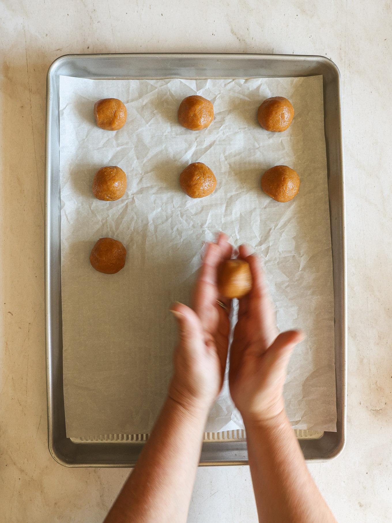 close-up of raw peanut butter cookie dough balls on a baking sheet, ready for crisscross marks