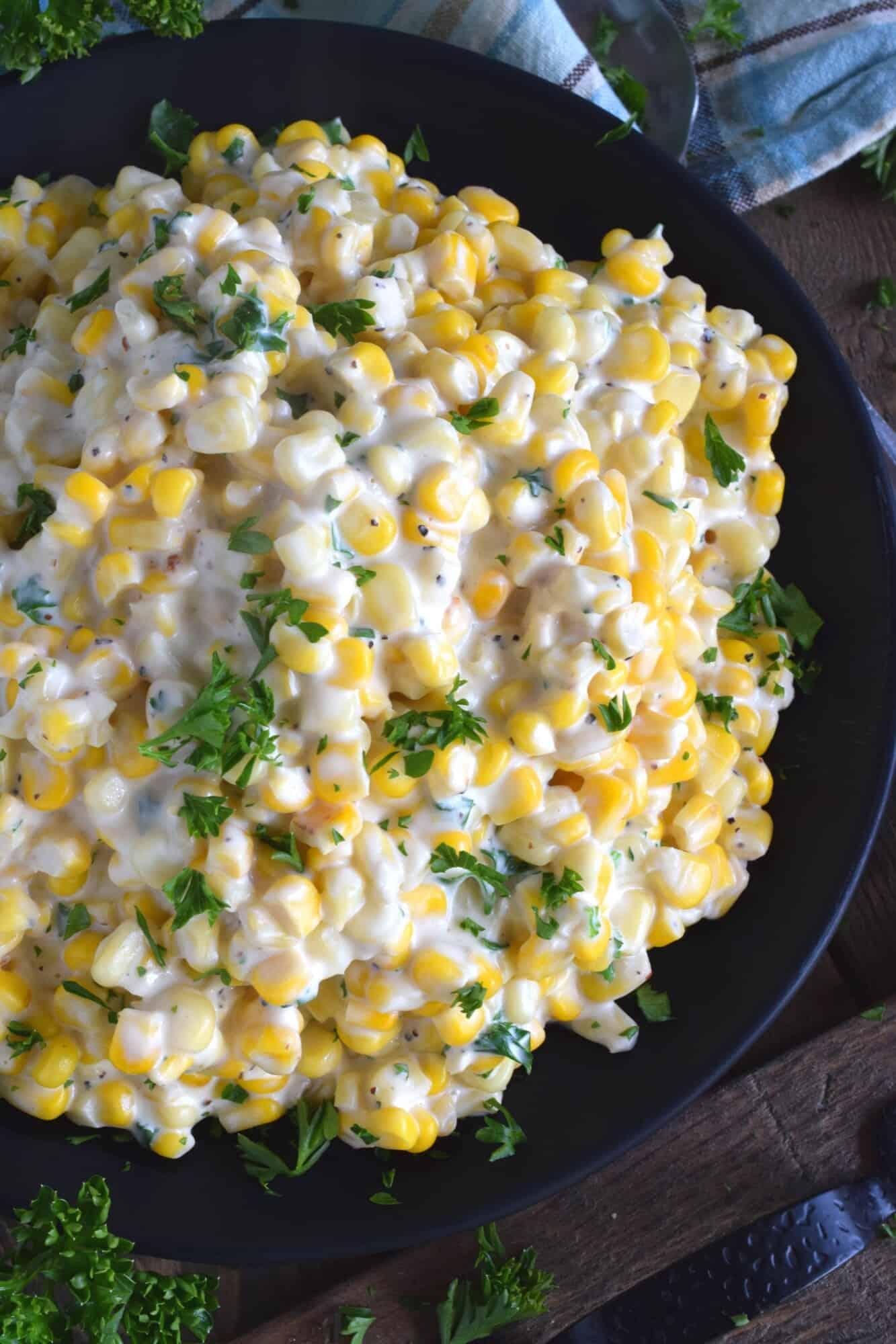 Overhead shot of fresh yellow corn kernels, cream cheese, butter, and seasonings laid out on a kitchen counter