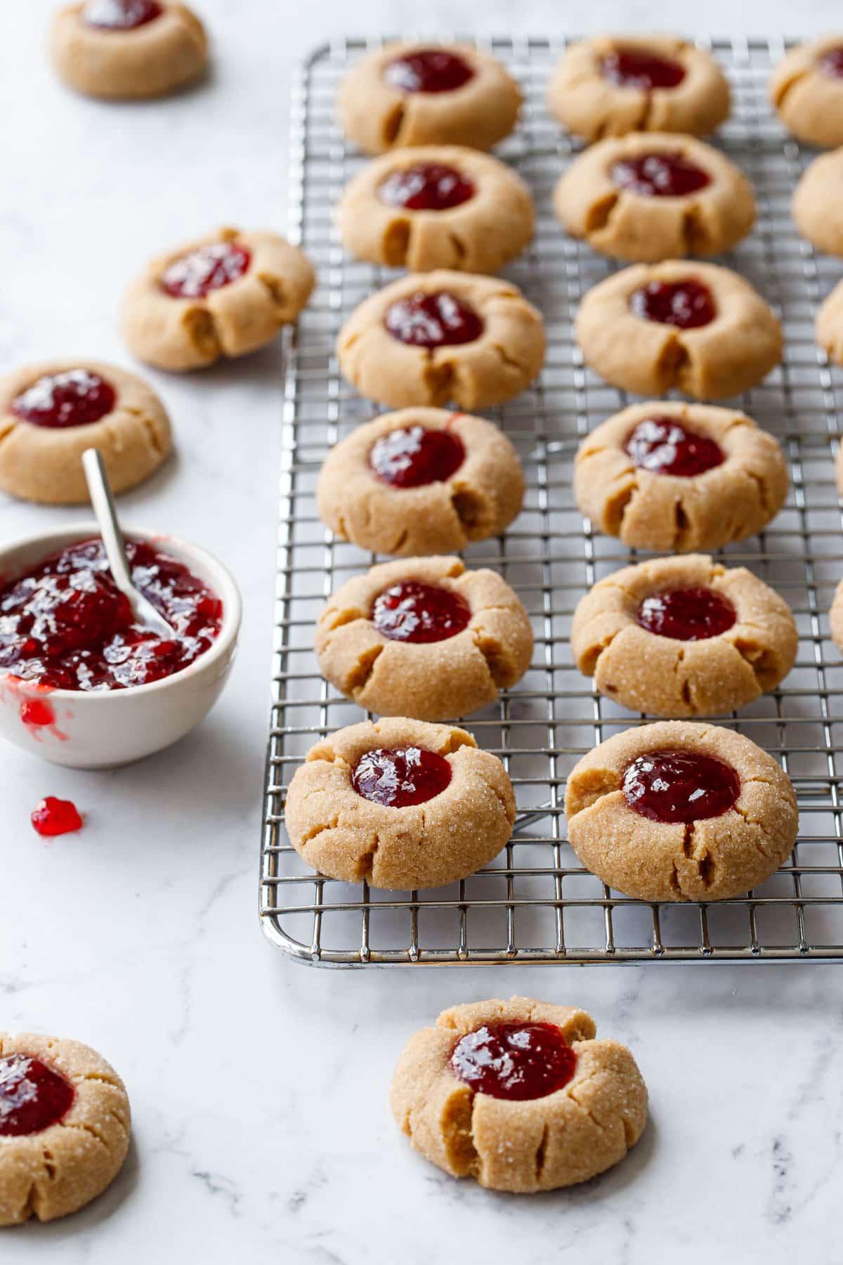 Freshly baked peanut butter and jam thumbprint cookies on parchment paper
