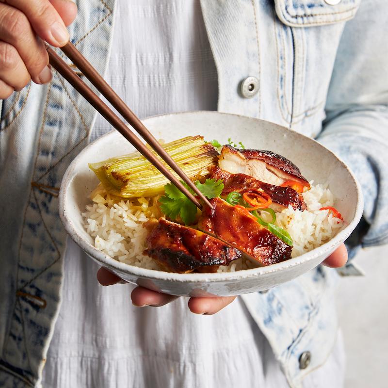 close up of sticky chicken rice bowl with chopsticks