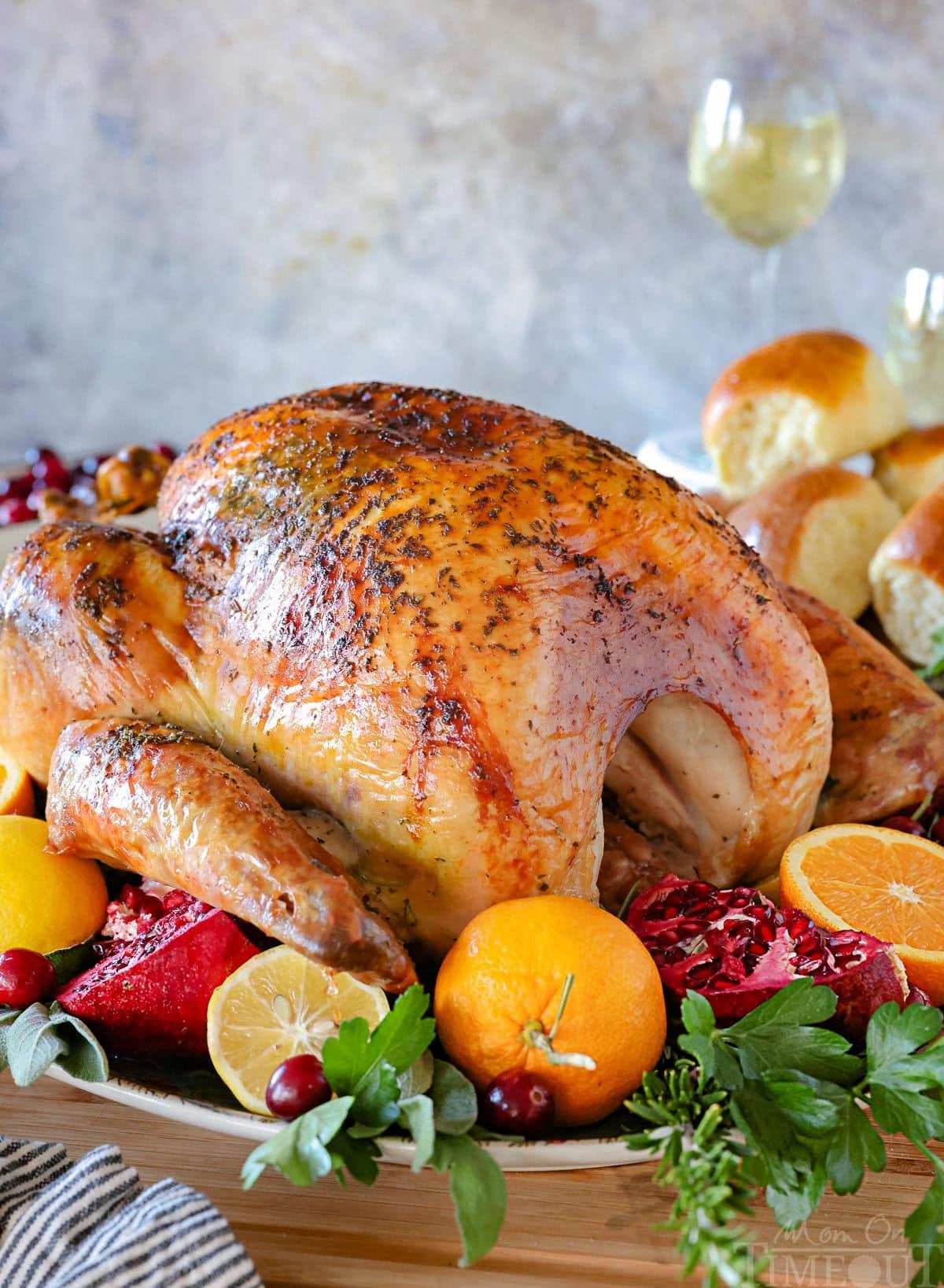 beautifully golden brown whole roasted turkey with herbs on a platter, ready to serve