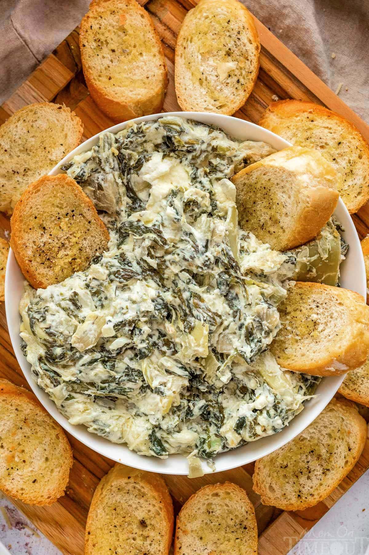 crockpot filled with spinach artichoke dip surrounded by dippers