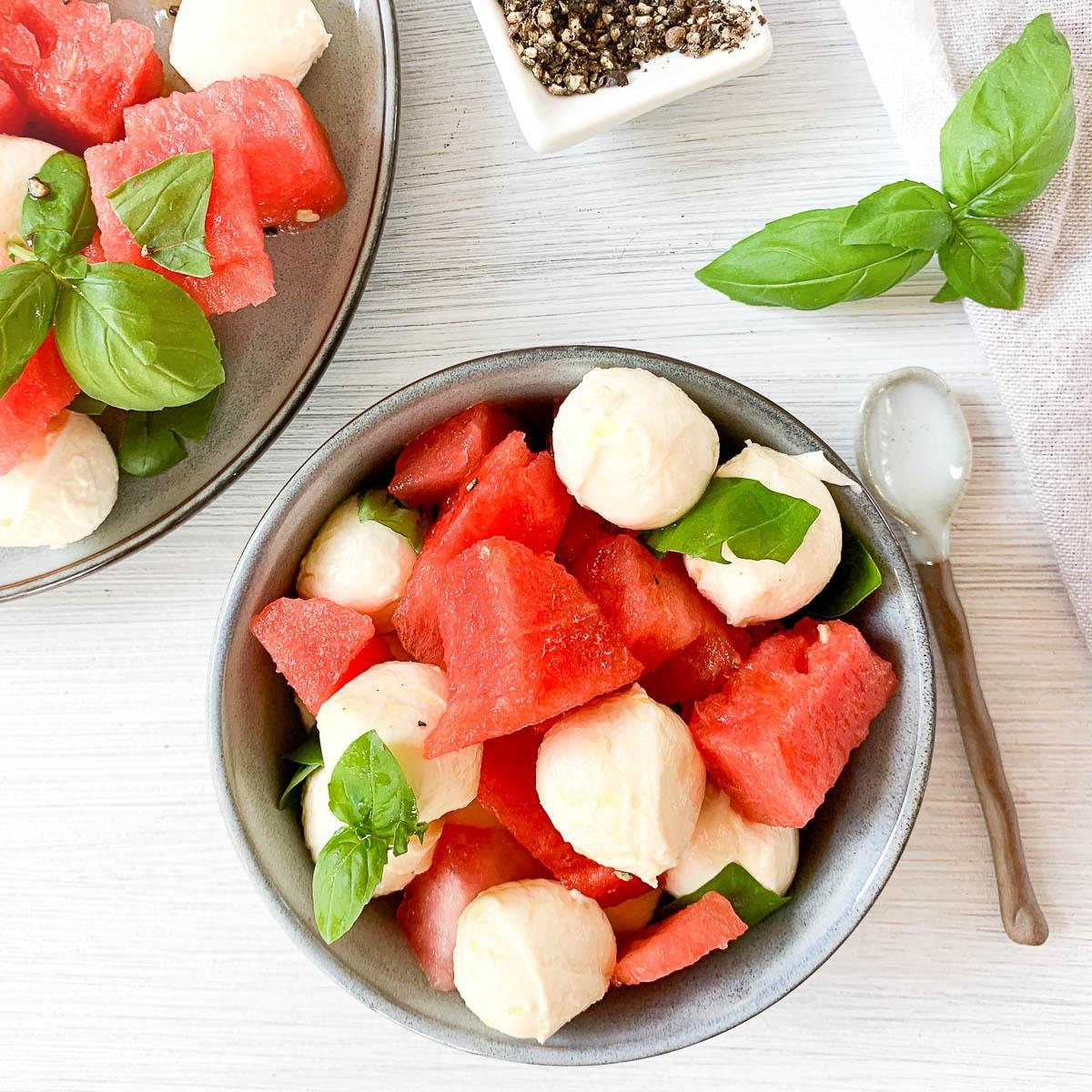 woman serving watermelon basil mozzarella salad outdoors