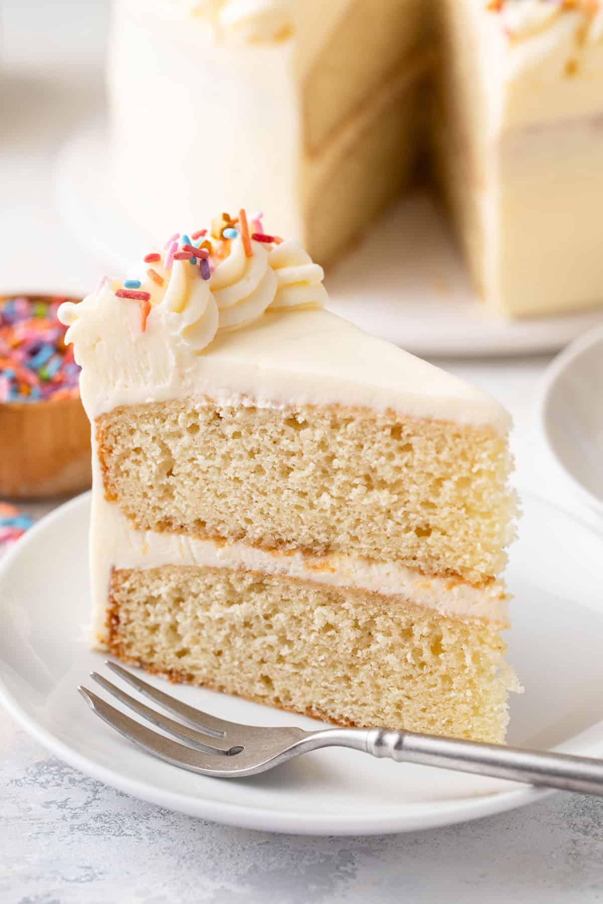 A slice of vanilla birthday cake with honeycomb toffee on a white plate