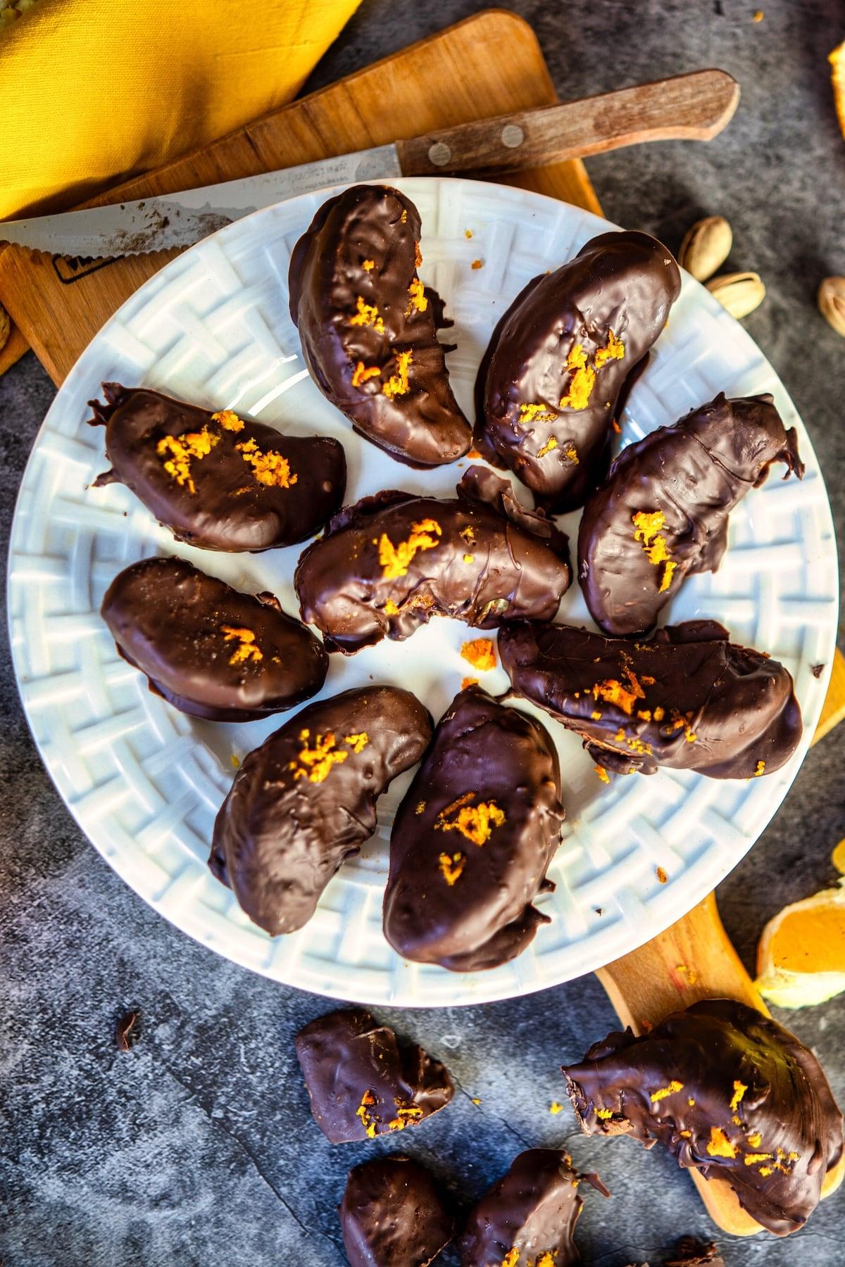 Hand grating fresh orange zest over a pile of dark chocolate chips