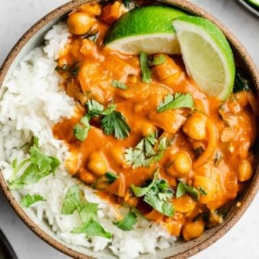 A close-up shot of chickpea curry being served over rice with fresh cilantro garnish