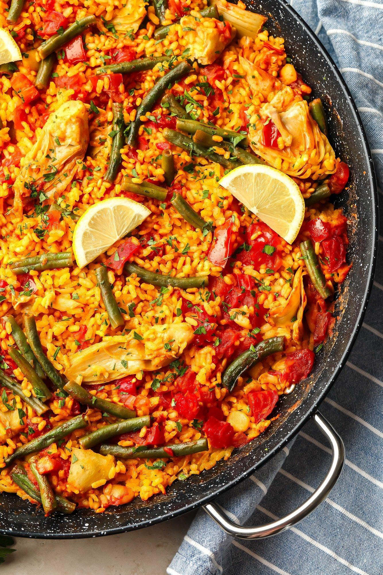 A vibrant paella in a large pan, with seafood and colorful vegetables