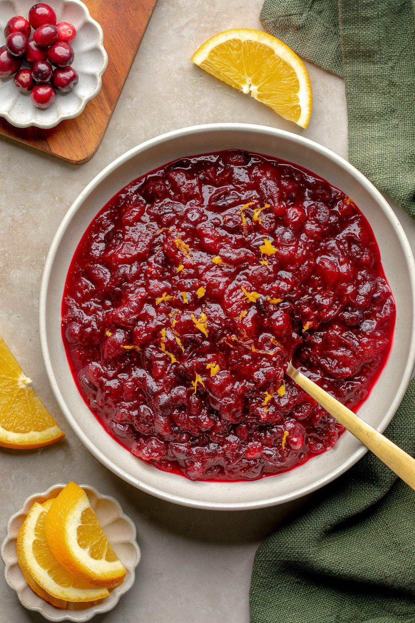 vibrant homemade cranberry sauce with fresh orange slices and zest in a serving bowl