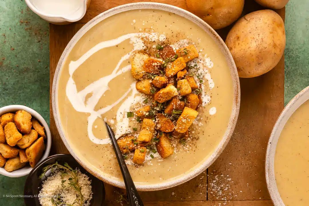 Overhead shot of a steaming bowl of potato soup with a spoon, cozy kitchen background