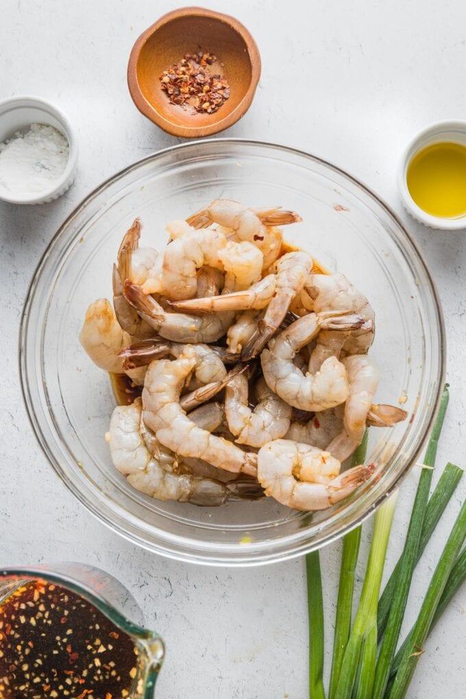 fresh raw shrimp marinating in a bowl with honey, garlic, and soy sauce