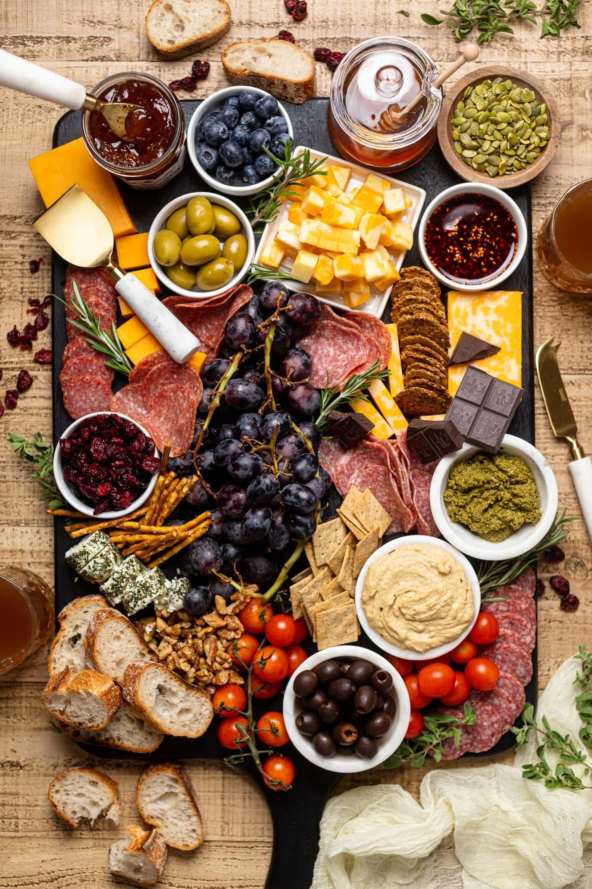 Overhead shot of a full, vibrant charcuterie board with a variety of cheeses, fruits, nuts, and breads