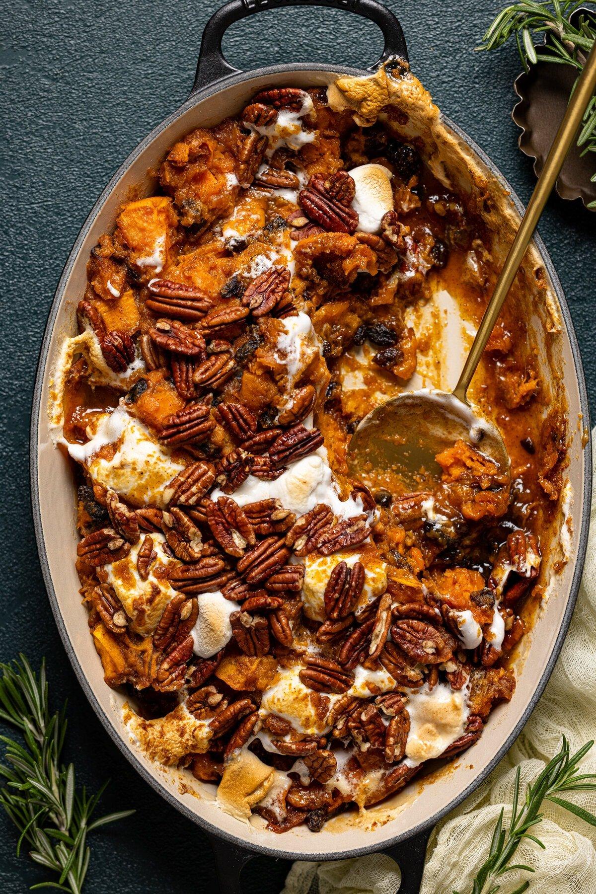 Close-up shot of maple sweet potato casserole with a spoon scooping a portion, showing creamy texture and crunchy topping