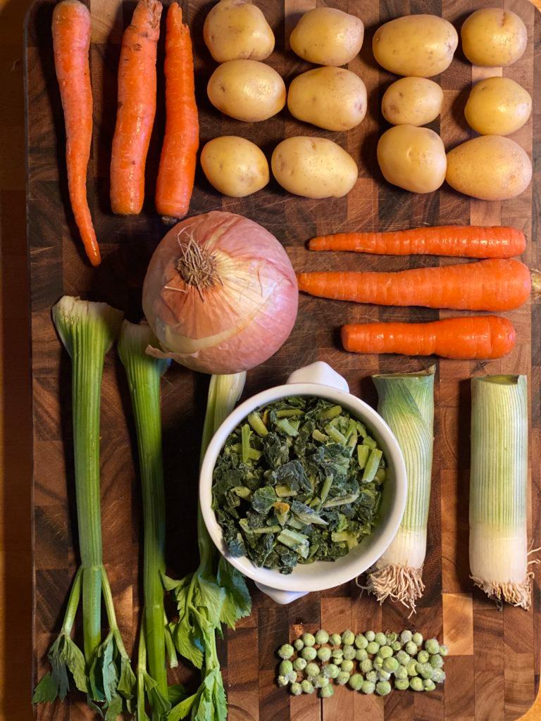 chopped fresh winter vegetables on a wooden cutting board, ready for soup