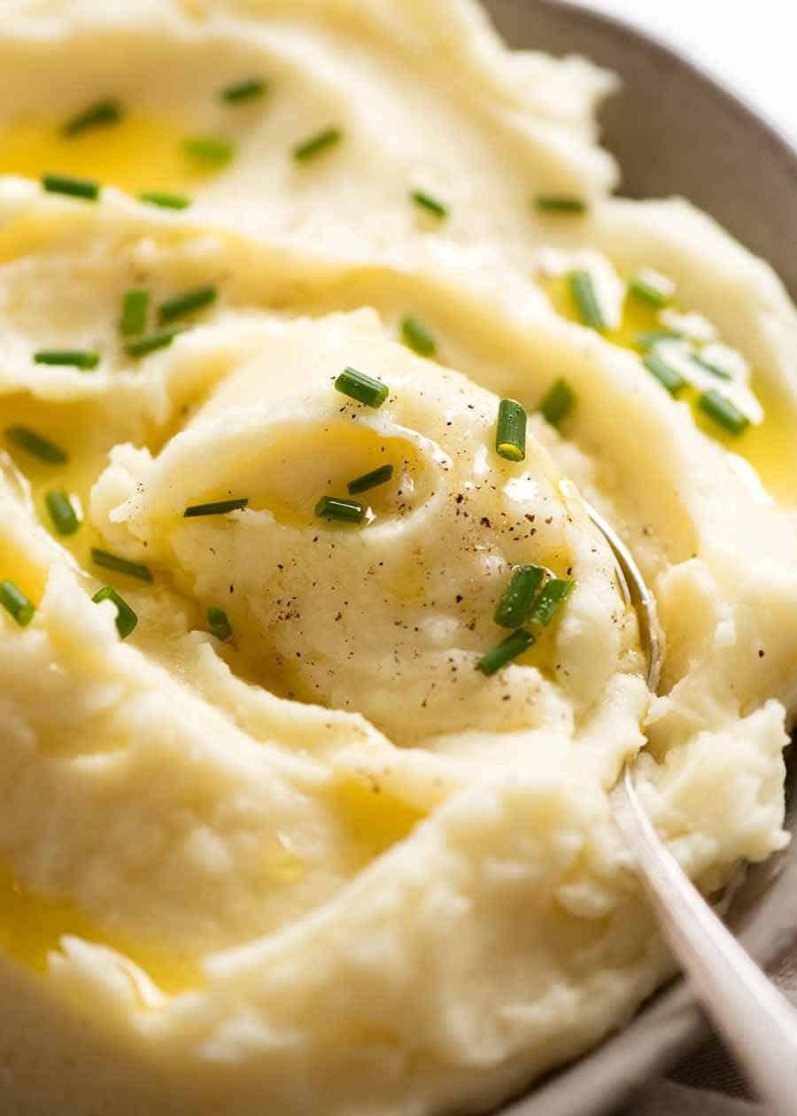 close-up of a spoon scooping creamy mashed potatoes from a serving bowl