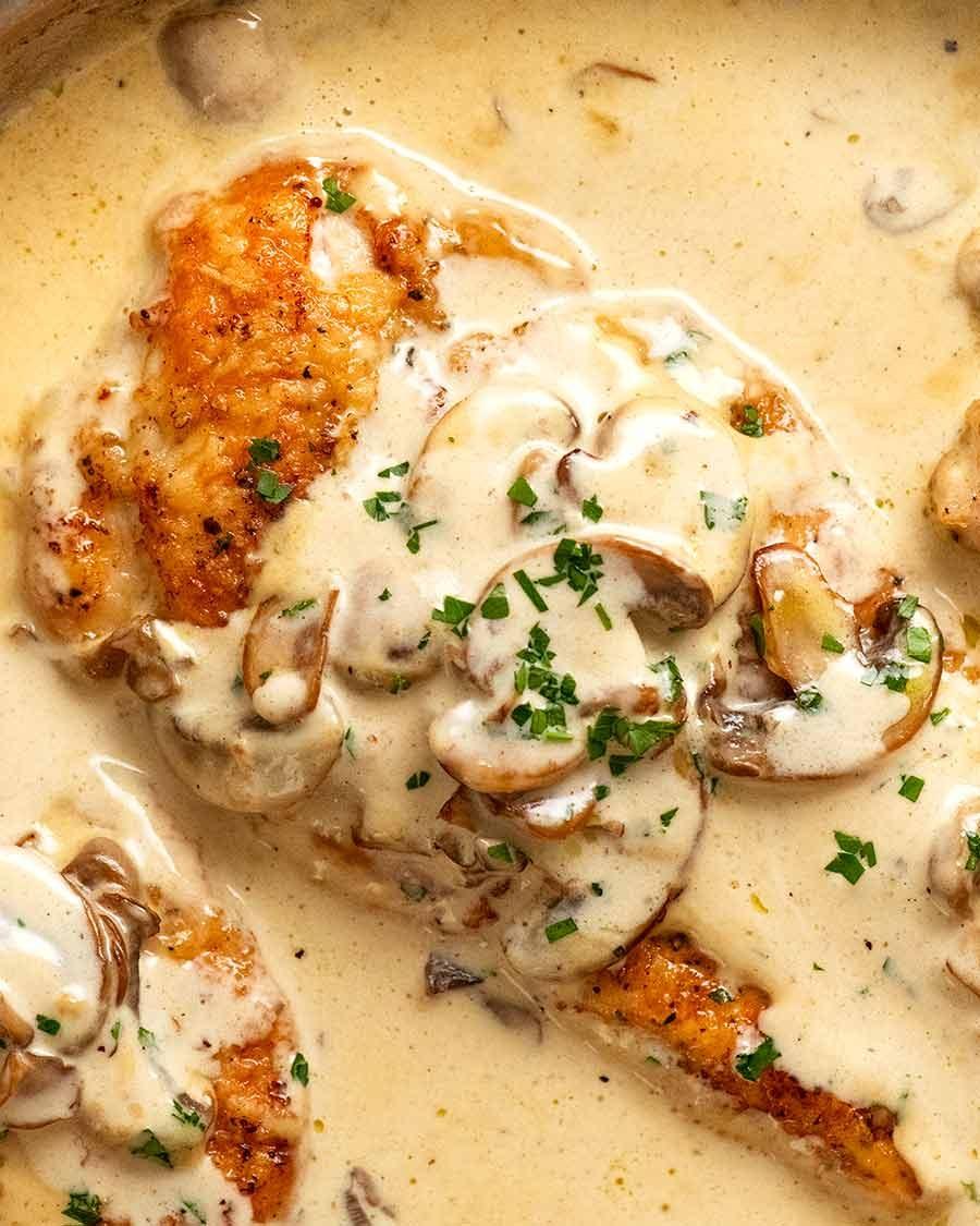 Close-up of a skillet with cream-seared chicken breast and bubbling sauce